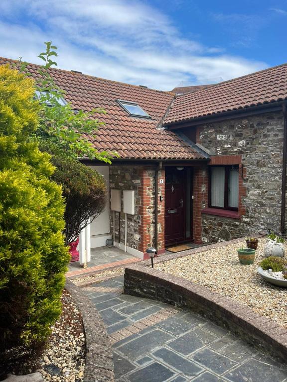 a brick house with a red roof and a driveway at The Rocks in Westward Ho