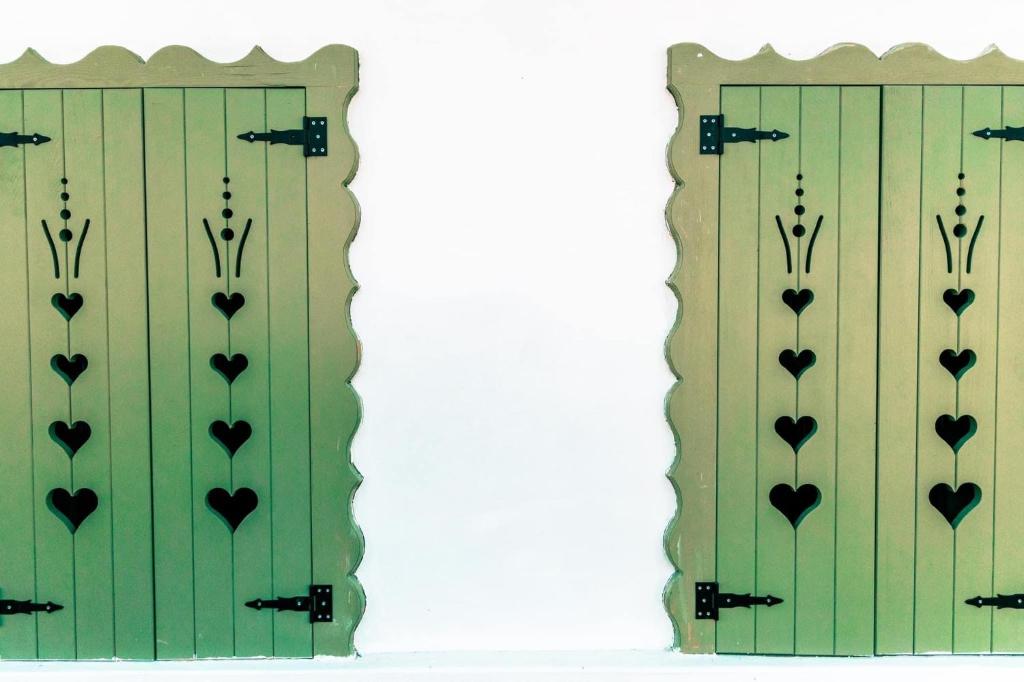 une paire de portes vertes avec le cœur sur elles dans l'établissement Kiskovász Pajta & Inn, à Nagytevel