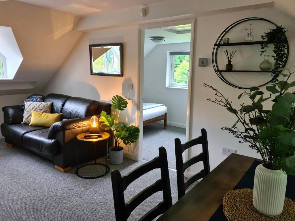 sala de estar con sofá de cuero negro y mesa en Park House Self-Contained Annex en Mold