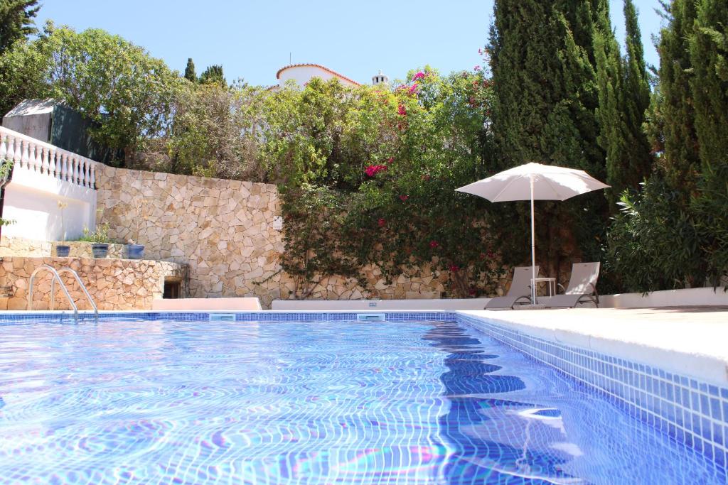a large swimming pool with an umbrella and an umbrella at Casa Carioca Carvoeiro in Carvoeiro