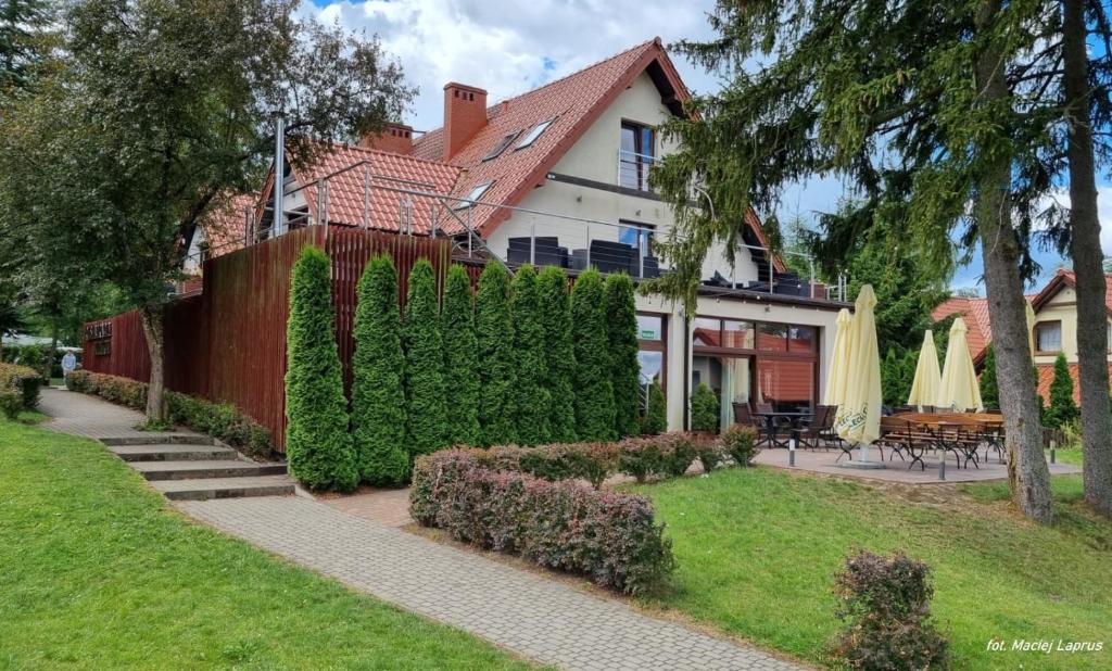 a house with a hedge in front of a yard at Vertigo Narie in Morąg