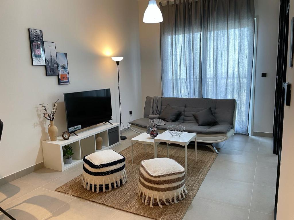 a living room with a couch and a tv at Dubai Hills Estate Deluxe 2 bedroom Apartment Collective Tower A 603 in Dubai