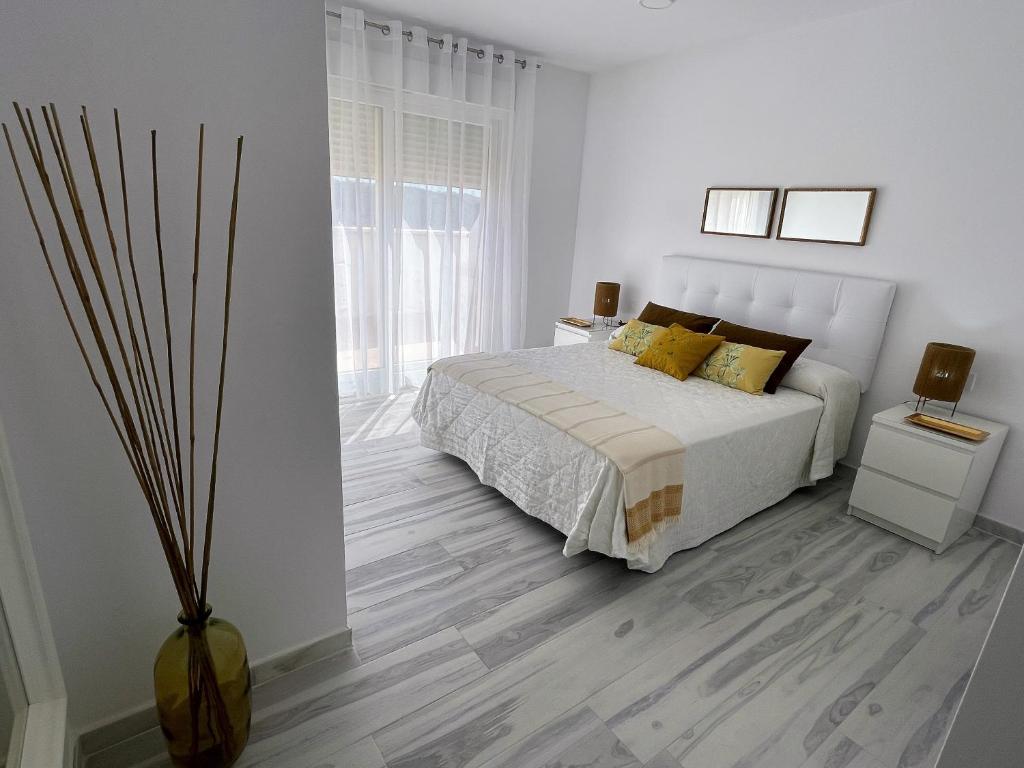 Dormitorio blanco con cama con almohadas amarillas en Apartamento Musa Tarifa, en Tarifa