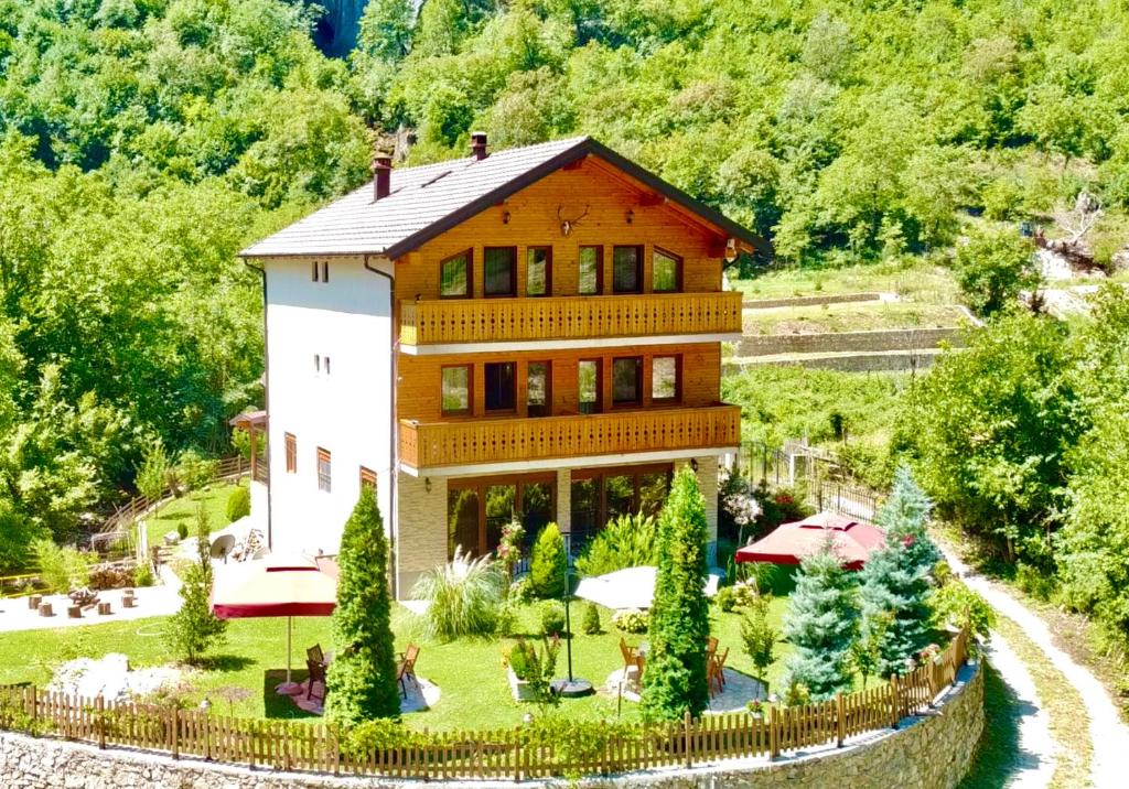 une grande maison sur une colline avec un jardin dans l'établissement Vila Alexander B&B, à Valbonë