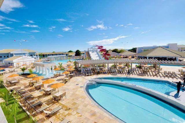 a large swimming pool with chairs and a resort at Caldas Novas Lacqua Di Roma IV - 2 banheiros e cozinha, piscina 24 horas in Caldas Novas