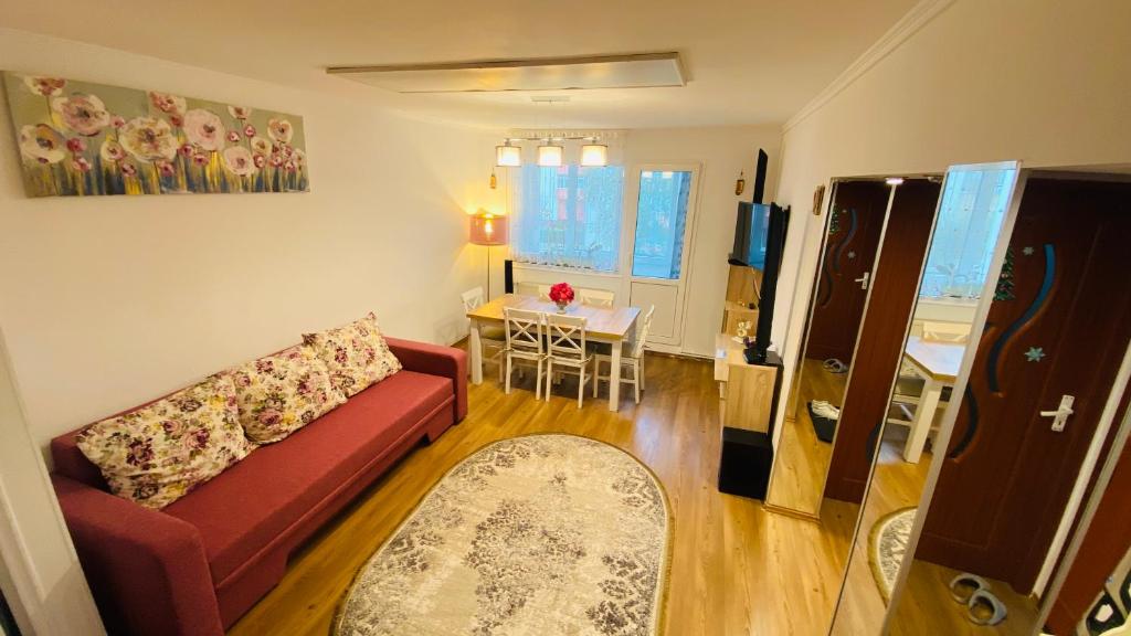 a living room with a red couch and a table at Oli's Mountain Apartment in Buşteni