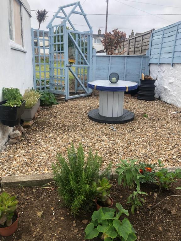 a patio with a table in a yard with plants at Carn View Located Nr Heartlands & Carn Brea in Pool
