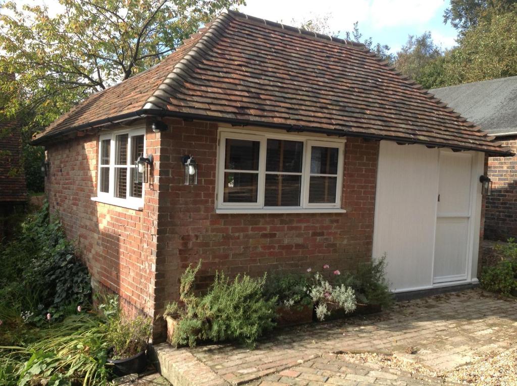a small brick house with a white garage at The Hideaway in Chelwood Gate