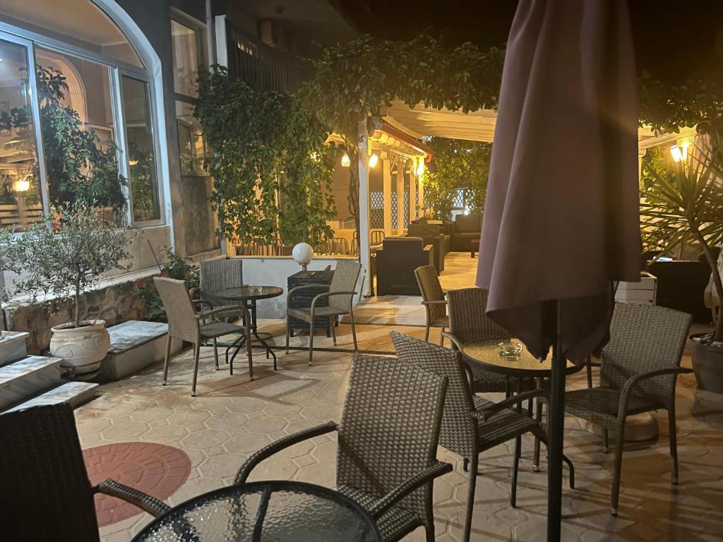 patio con sedie, tavoli e ombrellone di Hotel Pighi a Kriopigi