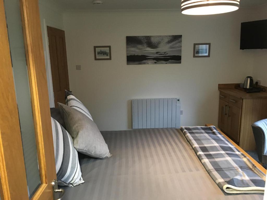 a bedroom with a bed with pillows and a television at Brecbennoch in Oban