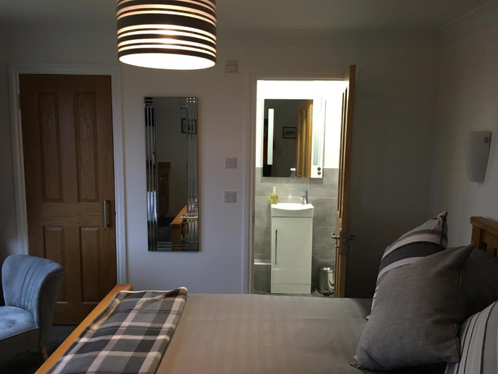 a bedroom with a bed and a bathroom with a sink at Brecbennoch in Oban