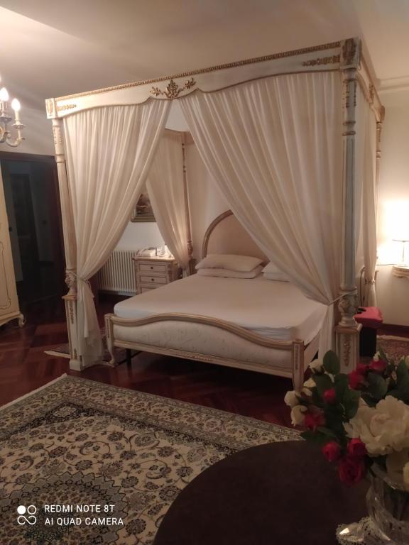 una camera con letto a baldacchino e tende bianche di Villa Maria a Benestare