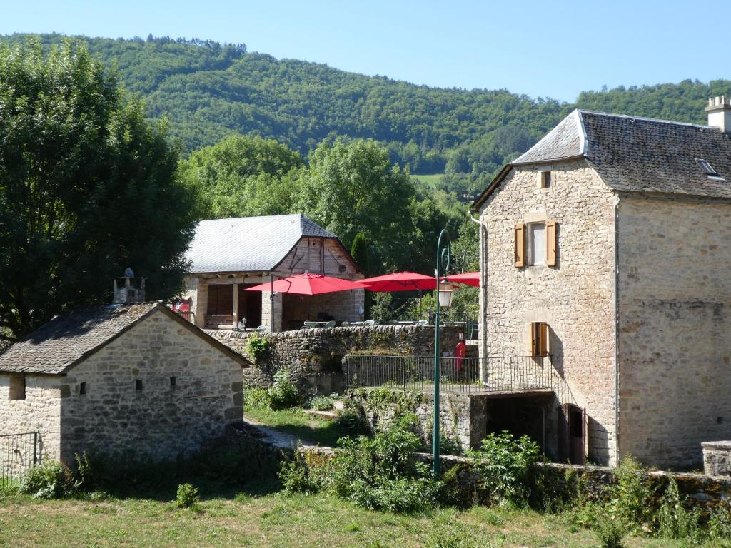 een oud stenen gebouw met rode parasols in een dorp bij Gîte insolite dans la Microbrasserie & Auberge Ortan in La Canourgue