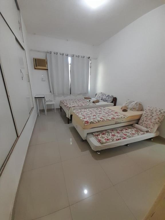 two beds in a room with white tile floors at Pousada Cantinho da Família in Rio de Janeiro