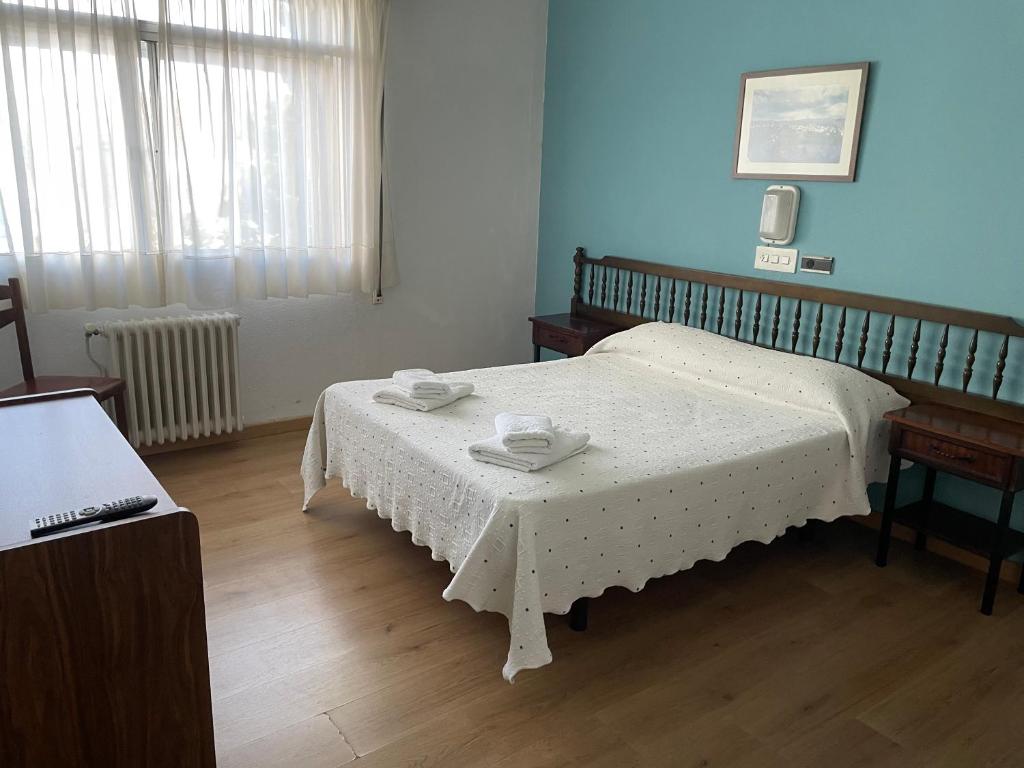 Hotel relojero في لا غودينيا: غرفة نوم بسرير وطاولة عليها صنفين