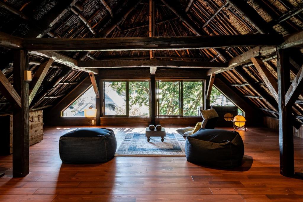 an attic living room with large windows and a couch at LiveGRACE House Lake Saiko 西湖古民家 in Yamanashi