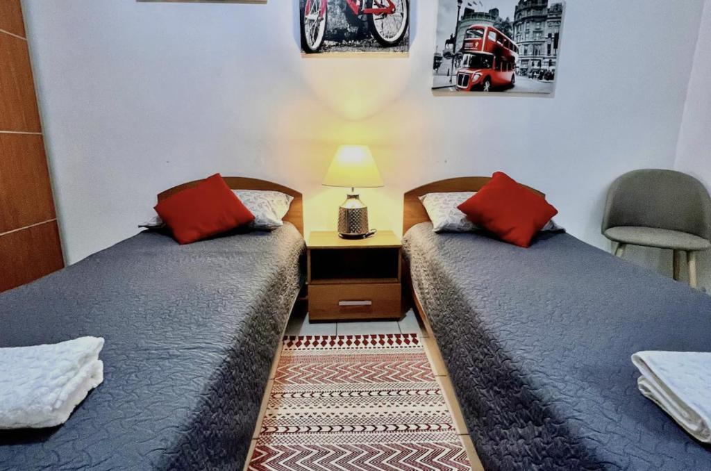 2 letti con cuscini rossi in una camera di F2 2 Lovely room, living and bathroom shared , St Julians a San Giuliano