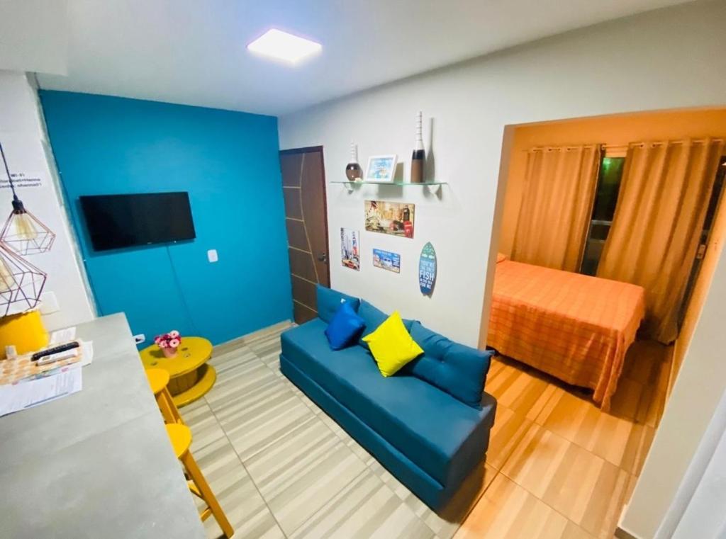 a living room with a blue couch and a bed at Studio A completo 400m da praia in Porto De Galinhas