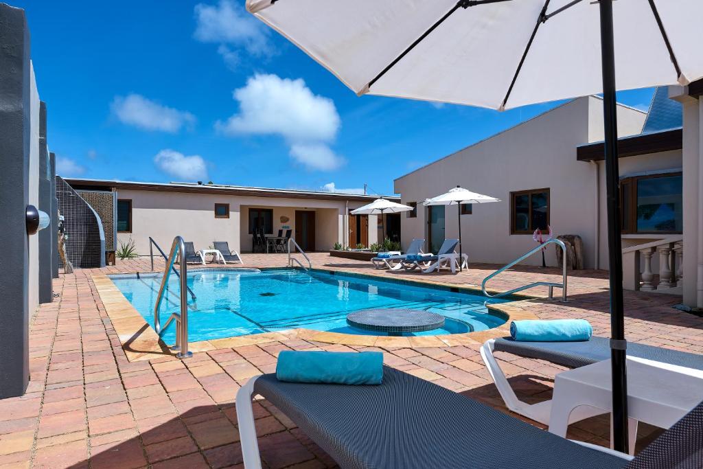 uma piscina com guarda-sol e cadeiras em Bubali Luxury Apartments - Adults Only - Wheelchair Friendly em Palm-Eagle Beach
