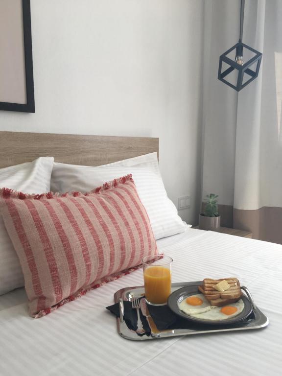 a breakfast tray with eggs and orange juice on a bed at Blue View Suites in Chorafakia