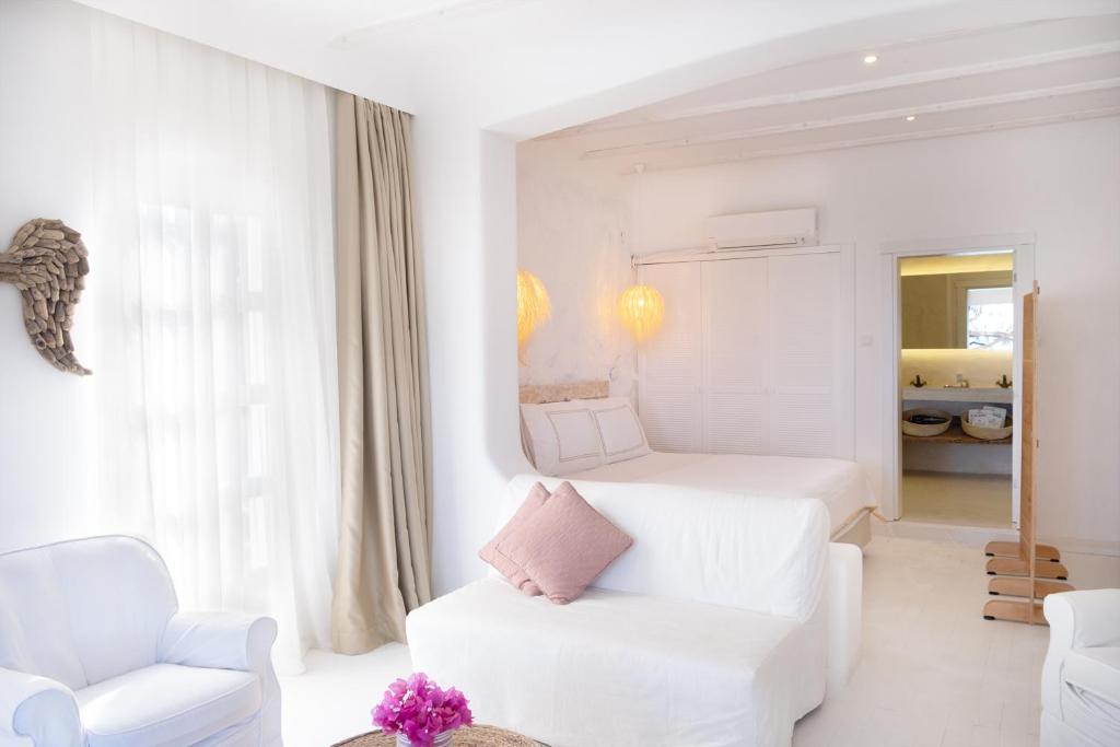 a white room with a bed and a couch and a chair at Yasos Suites in Çeşme