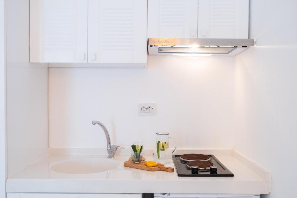 a white kitchen with a sink and a stove at Yasos Suites in Çeşme