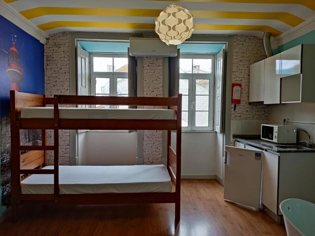 a room with a bunk bed and a kitchen at Meeting Hostel in Figueira da Foz