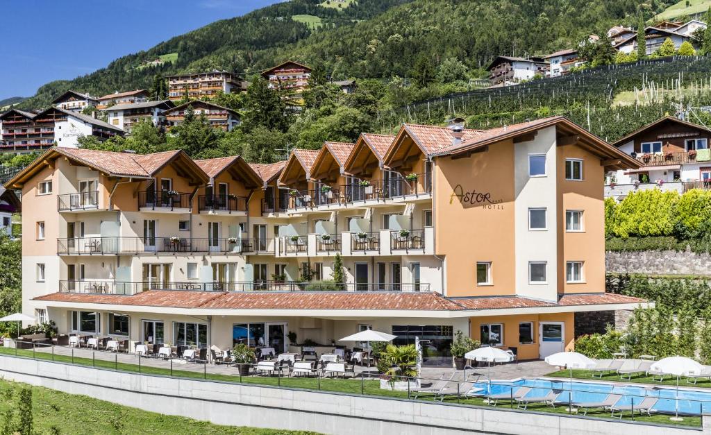 een hotel met een zwembad tegenover een berg bij Astor Hotel in Schenna