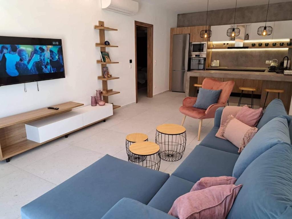 a living room with a blue couch and a tv at Courtyard Luxury Suites “MARIANTHI” in Pefki Rhodes