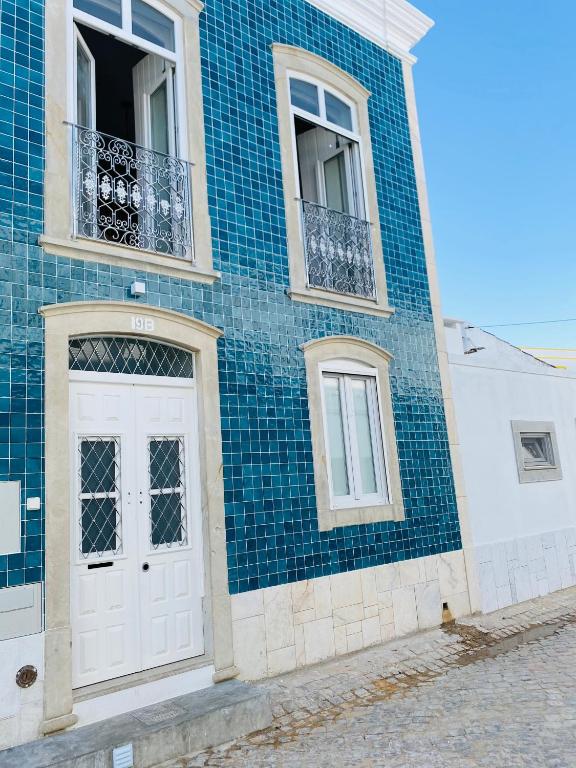 a blue tiled building with a white door and windows at A Casa Azul in Santa Luzia