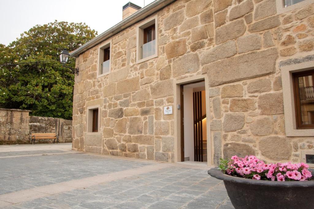 um edifício de pedra com um vaso de flores em frente em Marujita Vilanova, alojamiento singular em Vilanova de Arousa