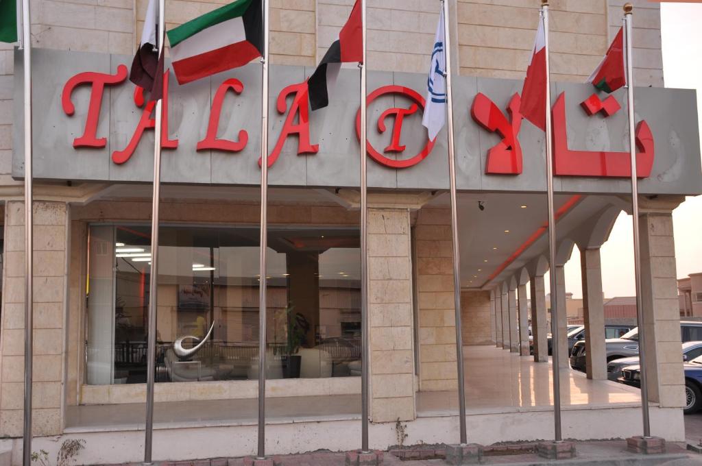 un hotel con banderas frente a un edificio en Tala inn, en Al Khafji