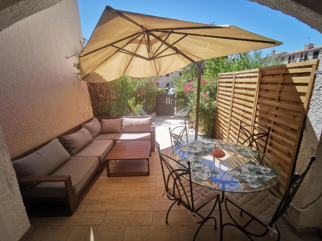 a patio with a table and a couch and an umbrella at La Terrasse Ensoleillée de Sausset : Le Citronnier in Sausset-les-Pins