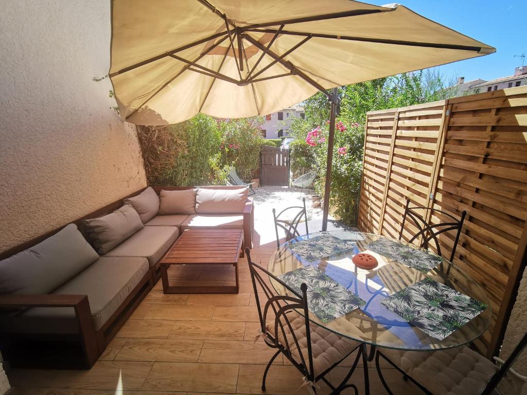 a patio with a couch and a table with an umbrella at La Terrasse Ensoleillée de Sausset : Le Citronnier in Sausset-les-Pins