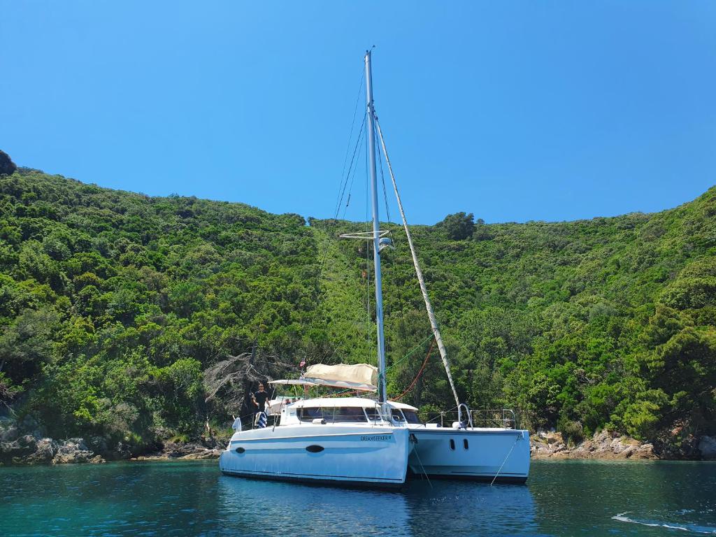 ein blaues Boot im Wasser neben einem Hügel in der Unterkunft Luxurious yachthouse in Korfu-Stadt