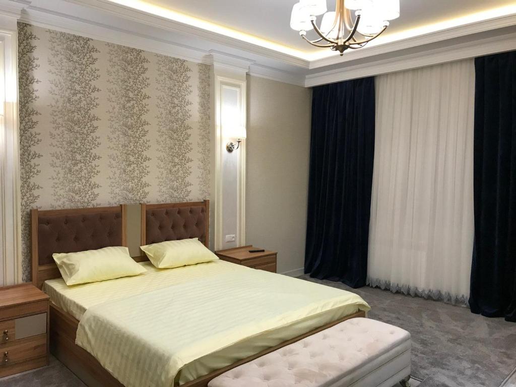 um quarto com uma cama e um lustre em Huvaydo Residence Apartment em Tashkent