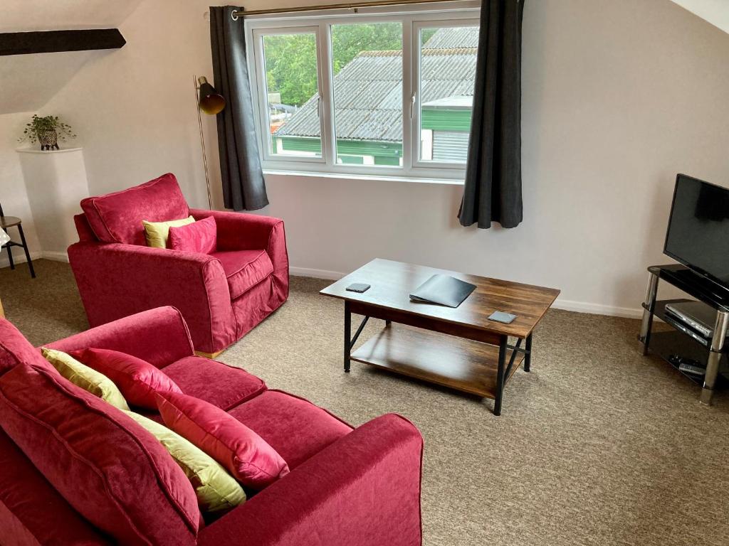 a living room with two red chairs and a coffee table at Briscoe Lodge Self Catering Apartments in Windermere