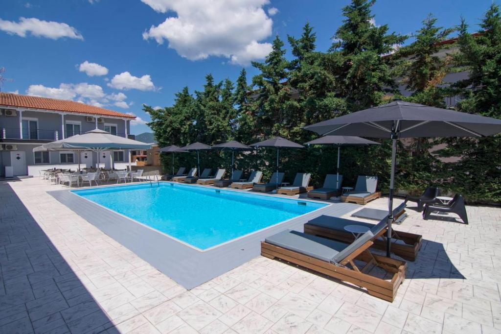 a swimming pool with lounge chairs and umbrellas at Philoxenia Suites in Nea Vrasna