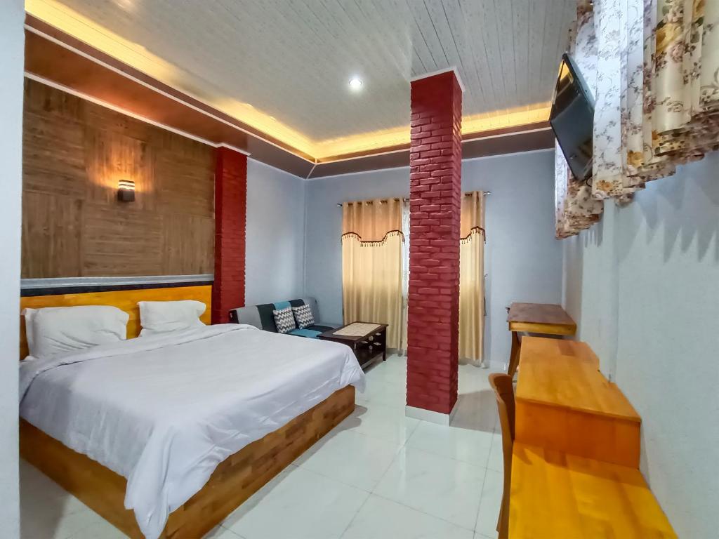 a bedroom with a bed and a desk and a television at Hotel New Dieng By Helocus in Berastagi