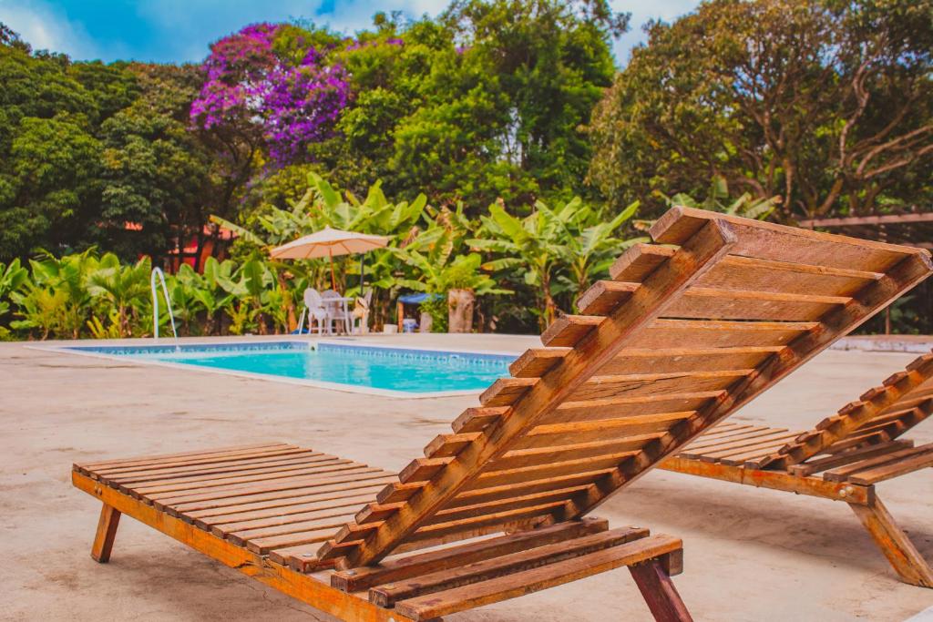 a wooden bench next to a swimming pool at Villaflor Pousada in Vale do Capao