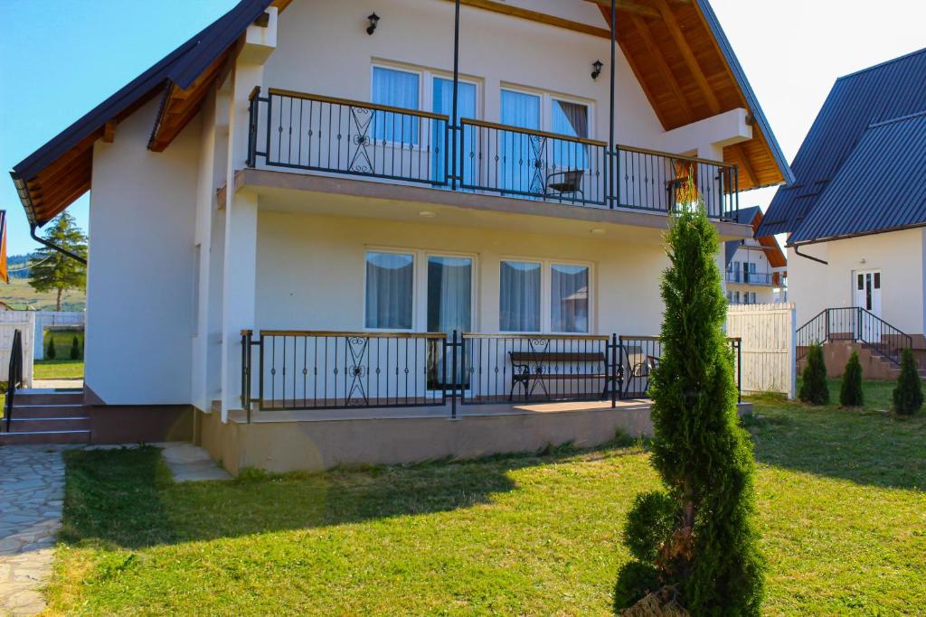 a house with a balcony and a grass yard at Oaza Mira Hotel & Resort-فندق ومنتجع واحة الهدوء in Vlasic