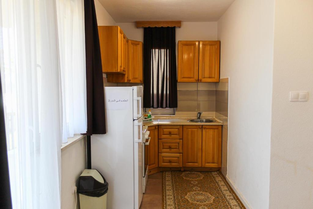 a small kitchen with wooden cabinets and a white refrigerator at Oaza Mira Hotel & Resort-فندق ومنتجع واحة الهدوء in Vlasic