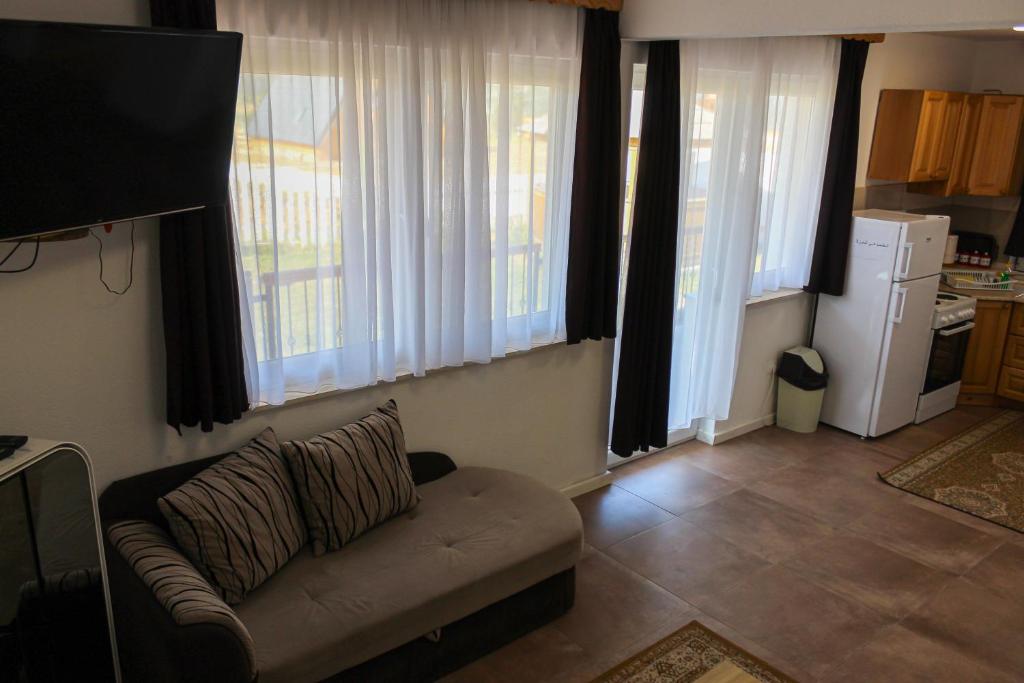 a living room with a couch and some windows at Oaza Mira Hotel & Resort-فندق ومنتجع واحة الهدوء in Vlasic