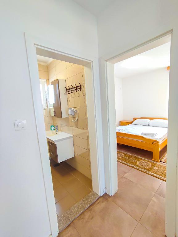 a bedroom with a bed and a bathroom with a sink at Oaza Mira Hotel & Resort-فندق ومنتجع واحة الهدوء in Vlasic