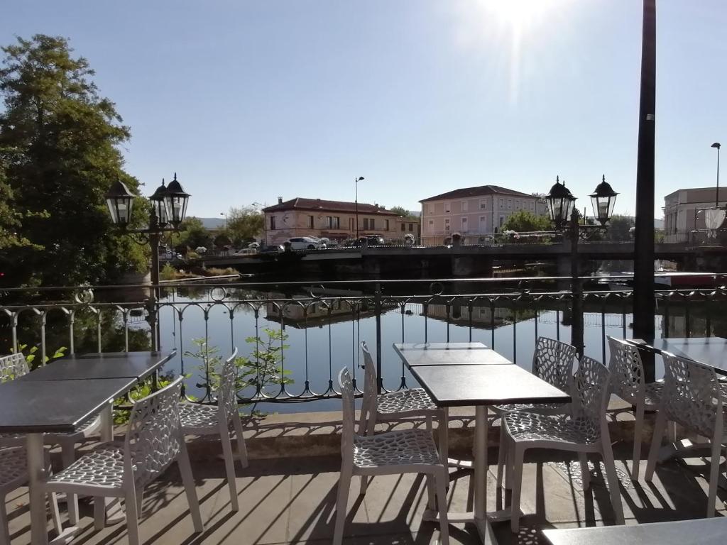 a patio with tables and chairs next to a body of water at Gîte Les Demoiselles des Sorgues in L'Isle-sur-la-Sorgue