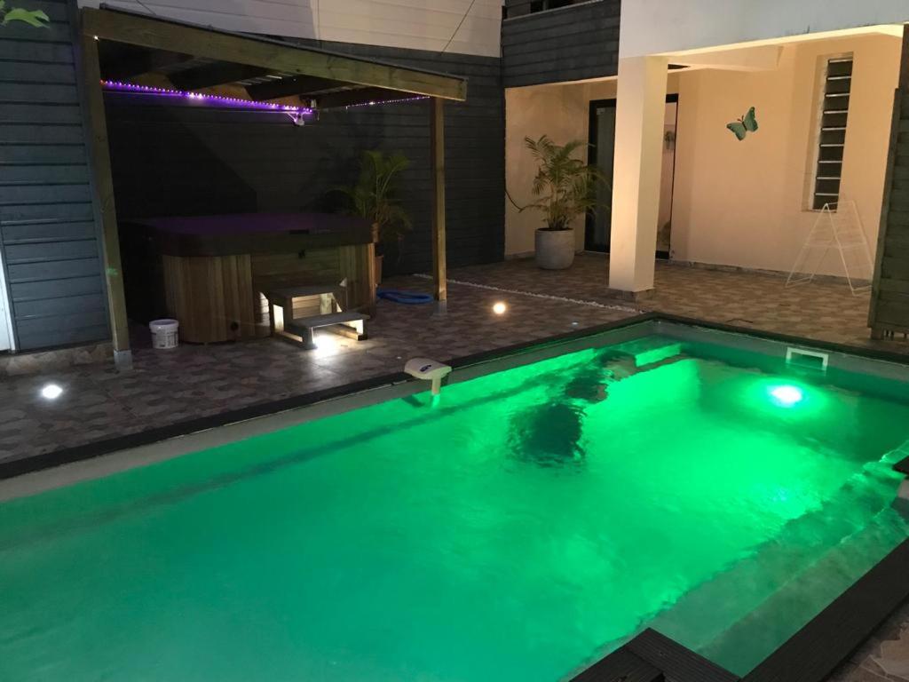 a swimming pool with green water in a house at Le Flamboyant avec piscine chauffée 30° et Jacuzzi in Saint-André