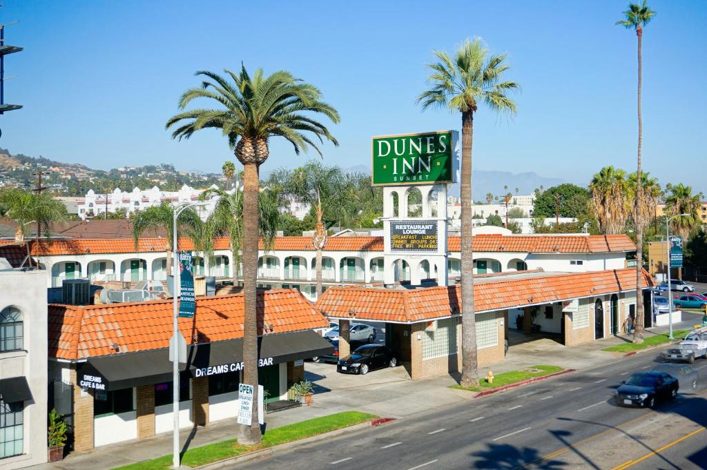 un cartello stradale di fronte a un edificio con palme di Dunes Inn - Sunset a Los Angeles
