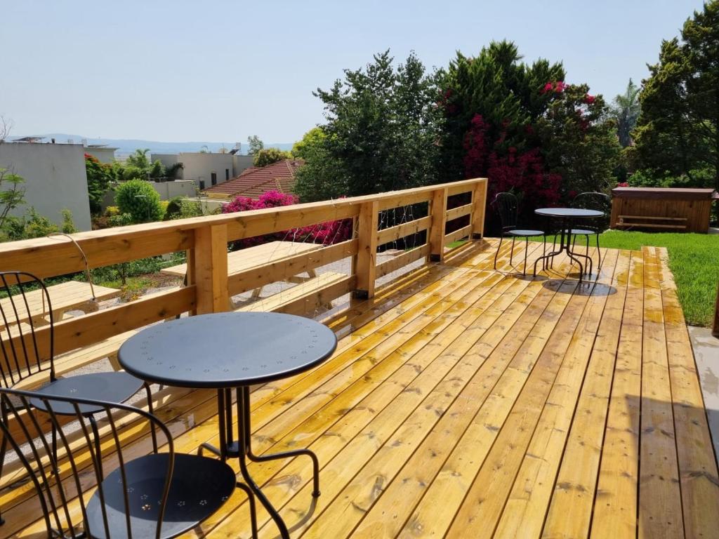 a wooden deck with tables and chairs on it at בית בעמק in Merhavyāh