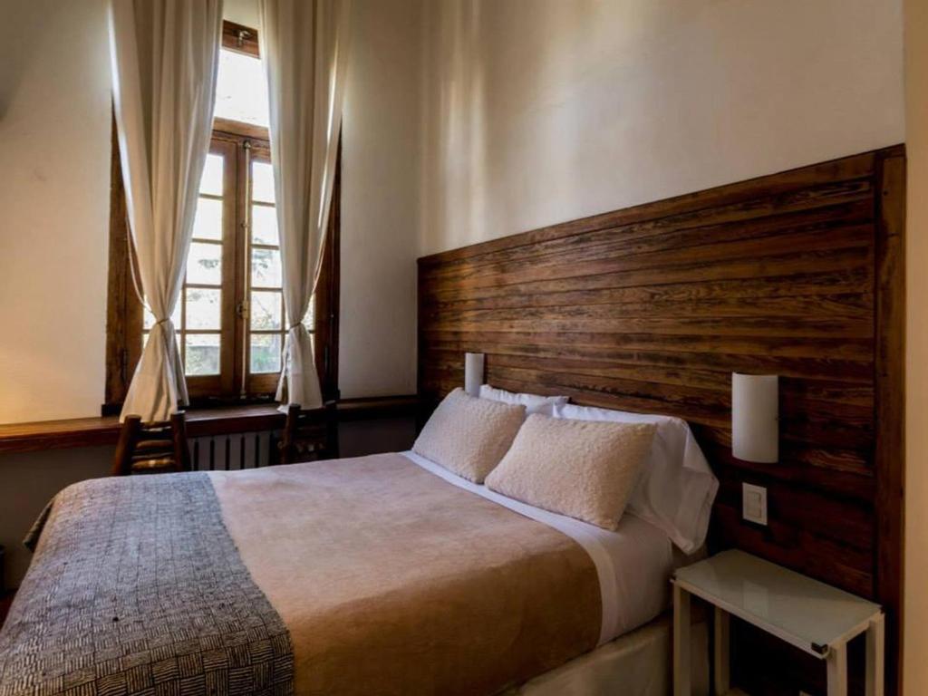 a bedroom with a large bed with a wooden headboard at Mousai Hotel Boutique in Capilla del Monte