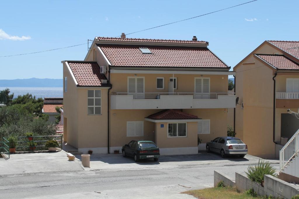 a house with two cars parked in a parking lot at Apartments with parking space Makarska - 6850 in Makarska